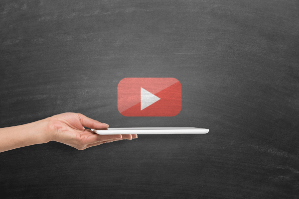 Simbolo do Youtube no centro e uma mão segurando um laptop embaixo no símbolo.